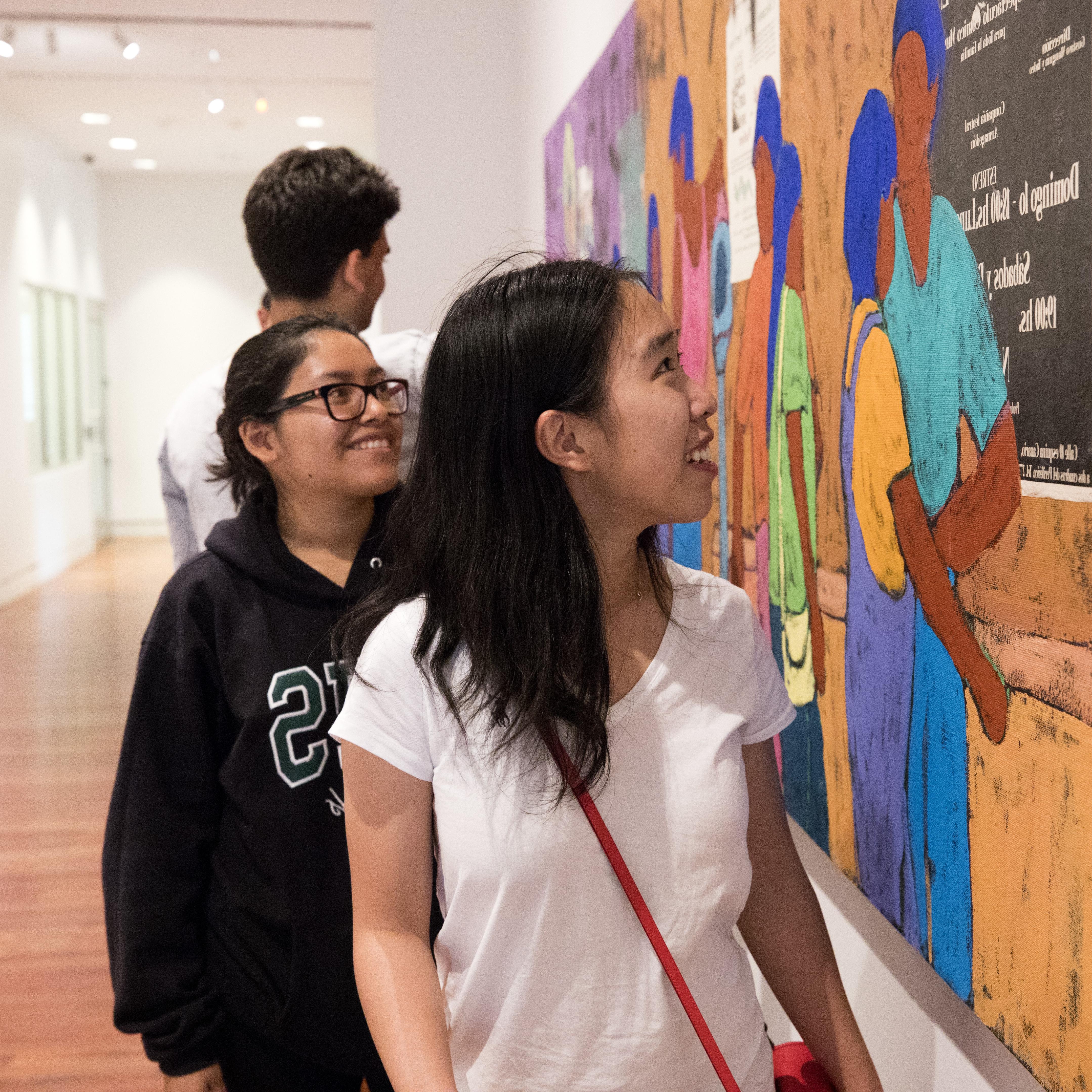 在美术中心，一名第一代学生正在看一幅西南壁画